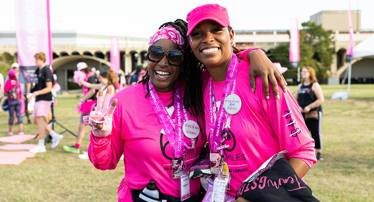 two African American women standing together wearing pink shirts