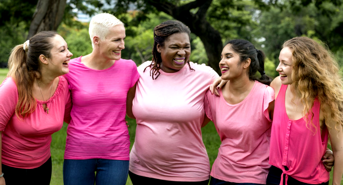 five diverse women standing together in pink shirts